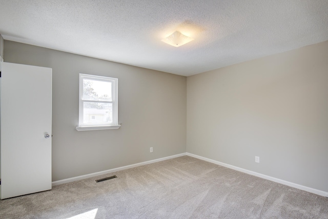 unfurnished room with light colored carpet and a textured ceiling