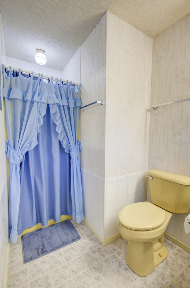 bathroom featuring walk in shower, a textured ceiling, and toilet