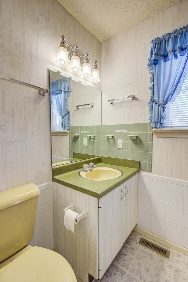 bathroom featuring vanity, a textured ceiling, tile walls, tile patterned flooring, and toilet