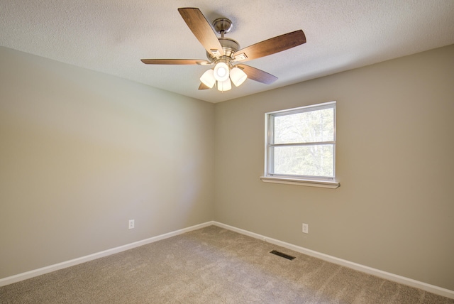 carpeted empty room with ceiling fan and a textured ceiling