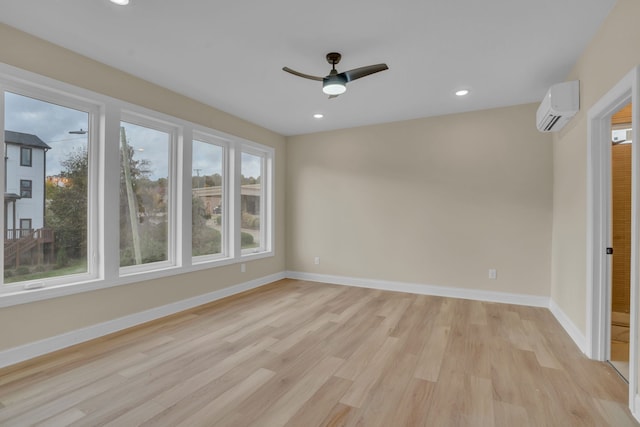 empty room featuring light wood-type flooring, a wall unit AC, and ceiling fan