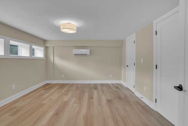 unfurnished room with a wall mounted AC and light hardwood / wood-style floors