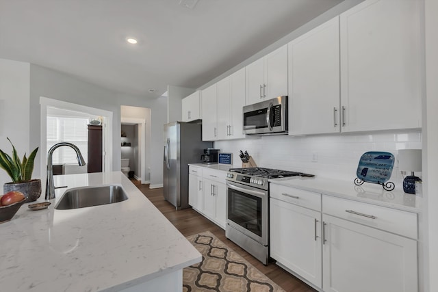 kitchen with light stone countertops, sink, white cabinets, and appliances with stainless steel finishes