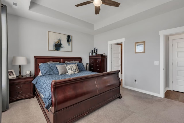 carpeted bedroom with ceiling fan and a tray ceiling