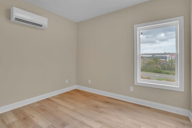 unfurnished room with light hardwood / wood-style flooring and an AC wall unit