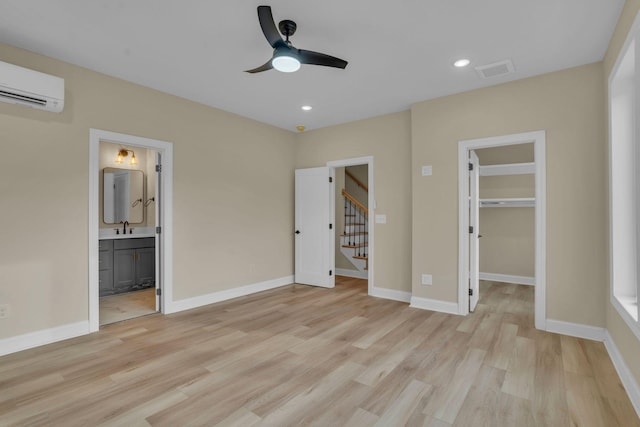 unfurnished bedroom with a spacious closet, ceiling fan, a closet, a wall mounted AC, and ensuite bath