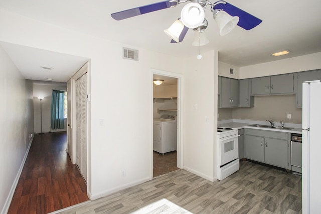 kitchen featuring washer / dryer, white electric range, sink, stainless steel dishwasher, and dark hardwood / wood-style flooring