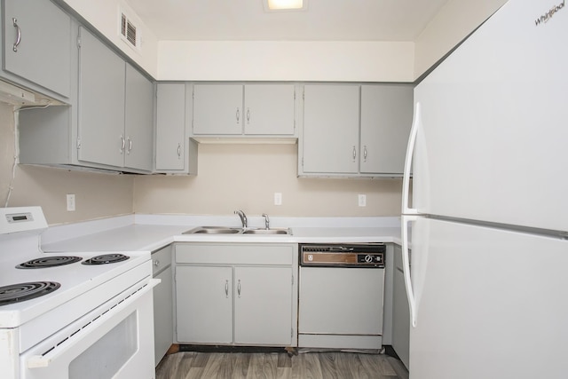 kitchen with sink, gray cabinetry, wood-type flooring, and white appliances