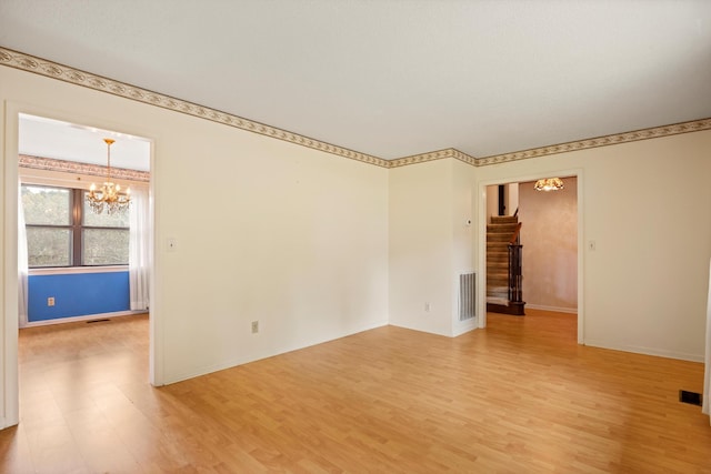 empty room with hardwood / wood-style floors and a chandelier