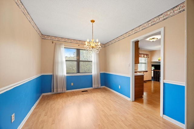 empty room featuring a textured ceiling, hardwood / wood-style flooring, and an inviting chandelier