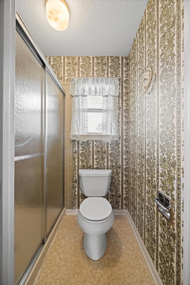 bathroom featuring toilet, a textured ceiling, and walk in shower