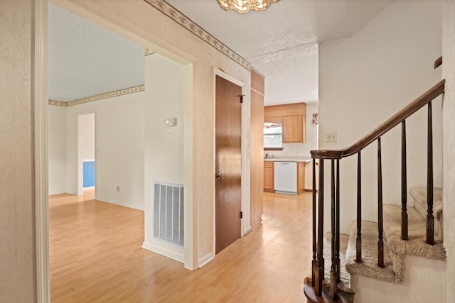 hall featuring a textured ceiling and light wood-type flooring