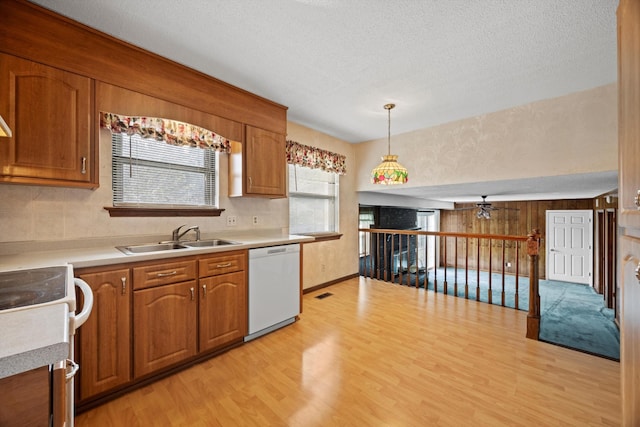 kitchen with sink, dishwasher, range, hanging light fixtures, and light hardwood / wood-style floors