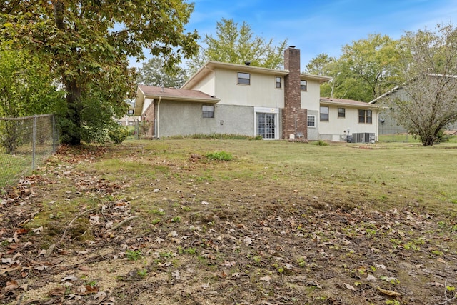 back of house with central air condition unit and a yard