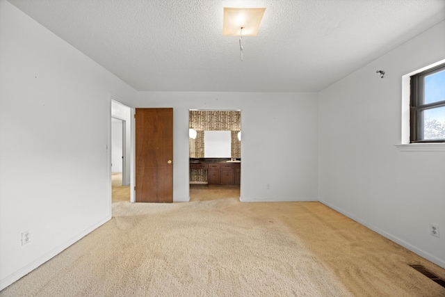 spare room featuring light carpet and a textured ceiling