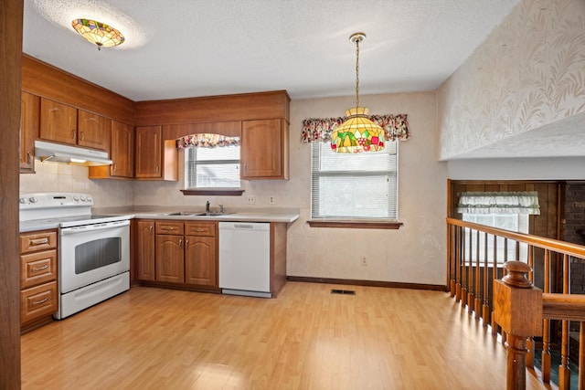 kitchen featuring white appliances, a textured ceiling, light wood-type flooring, and hanging light fixtures