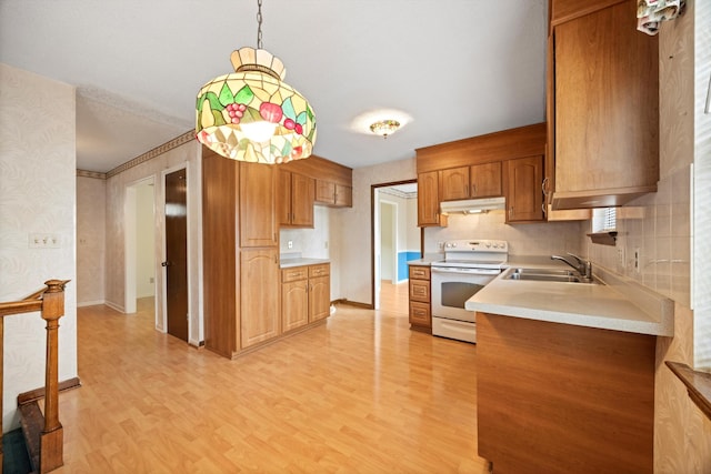 kitchen featuring hanging light fixtures, backsplash, sink, light hardwood / wood-style floors, and electric stove