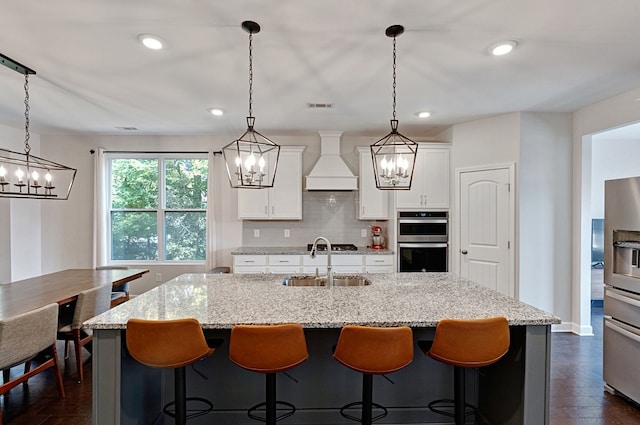 kitchen with premium range hood, pendant lighting, white cabinetry, and stainless steel appliances