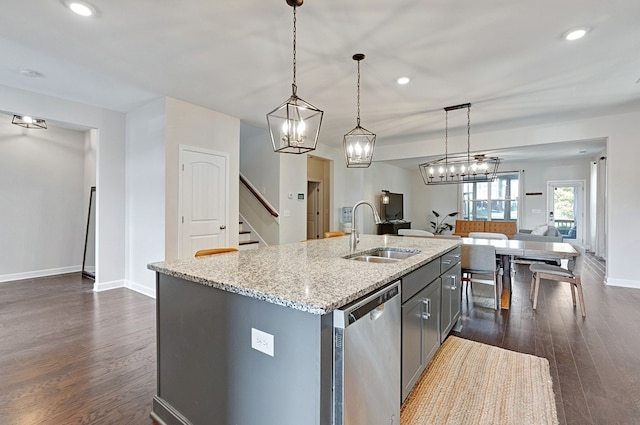 kitchen with an island with sink, stainless steel dishwasher, dark hardwood / wood-style floors, pendant lighting, and sink