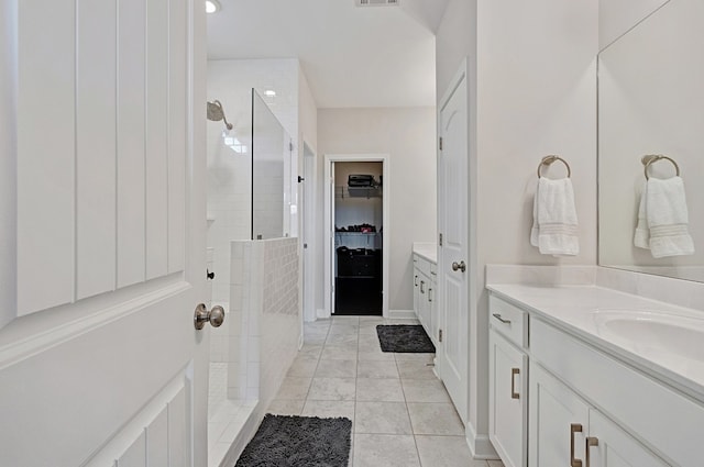 bathroom with a tile shower and vanity