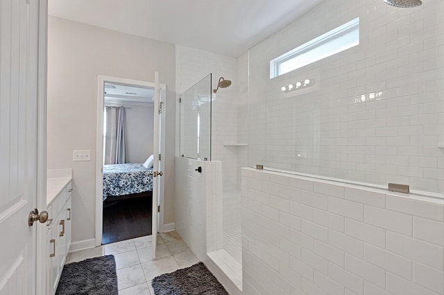 bathroom with tile patterned flooring, tiled shower, and vanity