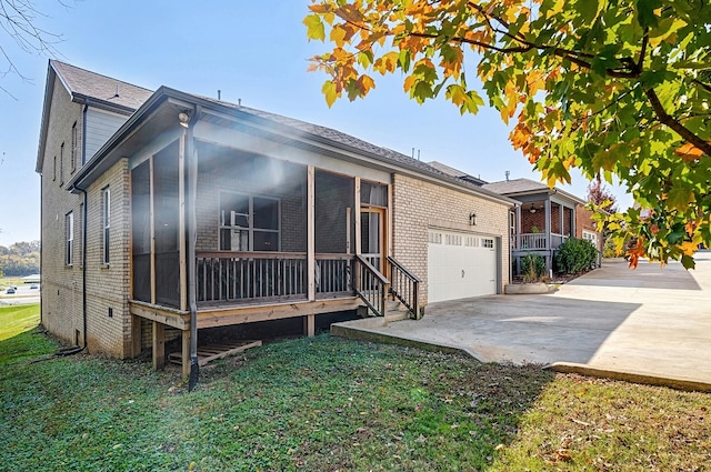 view of front of property with a front yard, a garage, and a sunroom