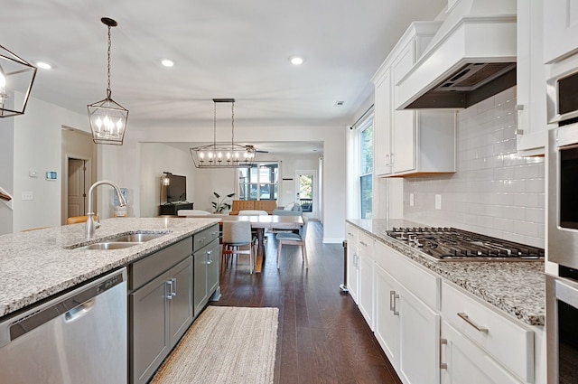 kitchen with dark wood-type flooring, stainless steel appliances, sink, pendant lighting, and white cabinetry