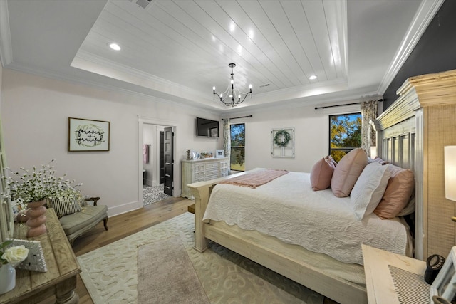 bedroom featuring a notable chandelier, ornamental molding, a tray ceiling, and hardwood / wood-style floors