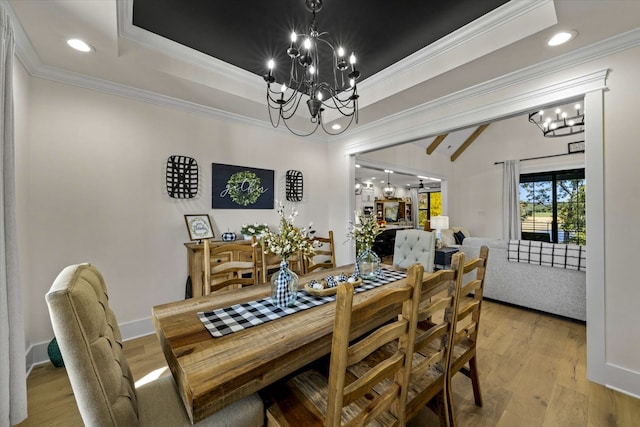 dining area featuring a notable chandelier, light hardwood / wood-style floors, crown molding, and a raised ceiling