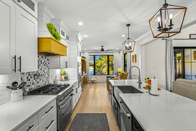 kitchen featuring white cabinets, light hardwood / wood-style flooring, pendant lighting, and stainless steel appliances