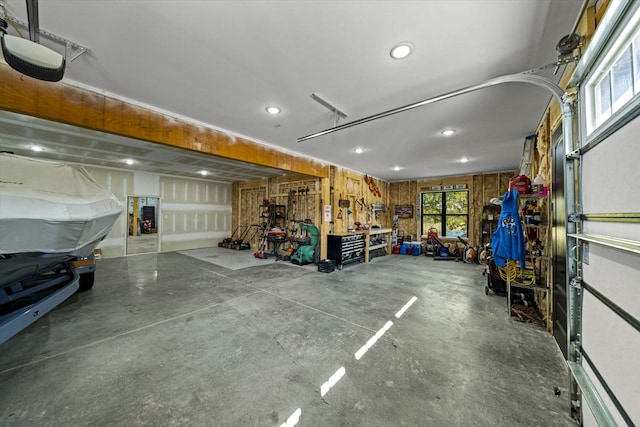 garage with a garage door opener, wooden walls, and a workshop area