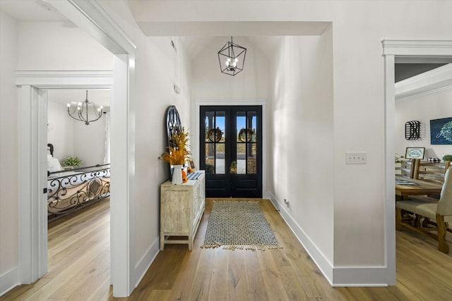 foyer with french doors, a chandelier, and light wood-type flooring