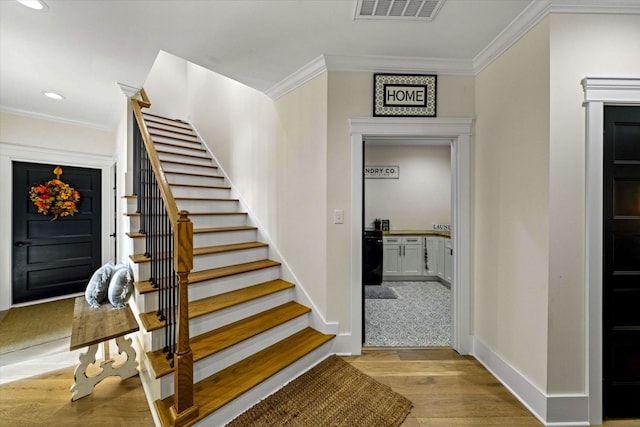 staircase with wood-type flooring and ornamental molding