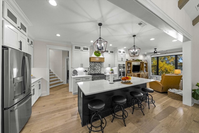 kitchen with appliances with stainless steel finishes, light hardwood / wood-style flooring, a kitchen island with sink, and white cabinets