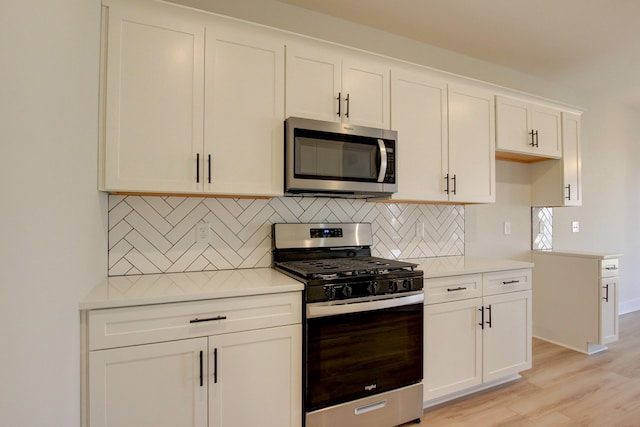 kitchen with light hardwood / wood-style flooring, tasteful backsplash, white cabinetry, and stainless steel appliances