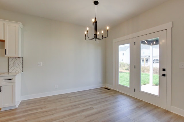 unfurnished dining area with light hardwood / wood-style flooring, a notable chandelier, and a healthy amount of sunlight