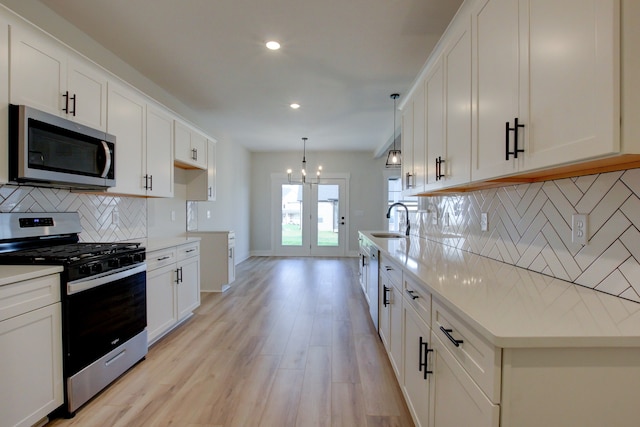 kitchen featuring stainless steel appliances, decorative backsplash, sink, light hardwood / wood-style floors, and white cabinets