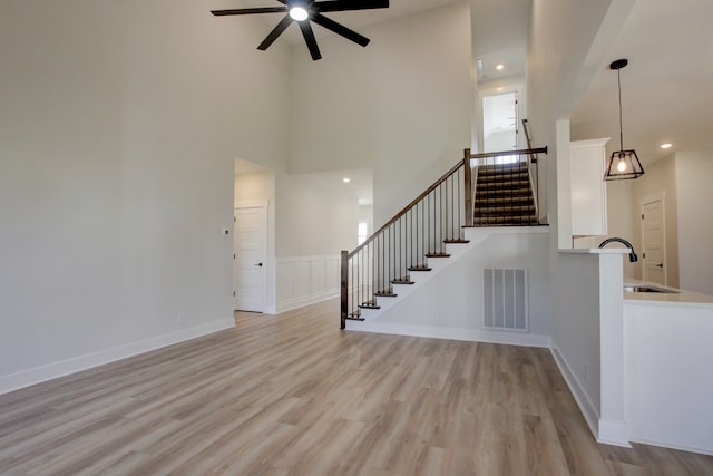 interior space with ceiling fan, light hardwood / wood-style floors, a high ceiling, and sink