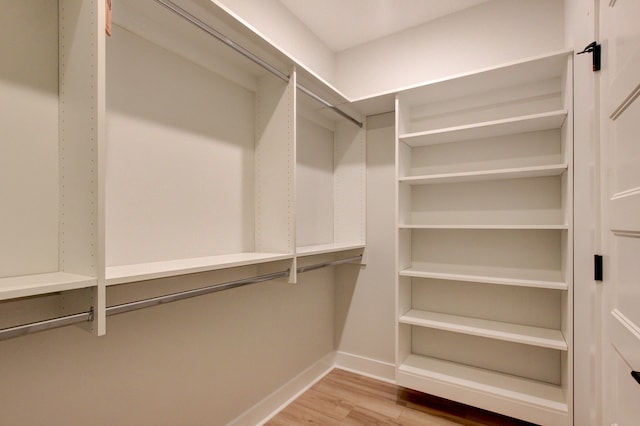 walk in closet with light hardwood / wood-style flooring