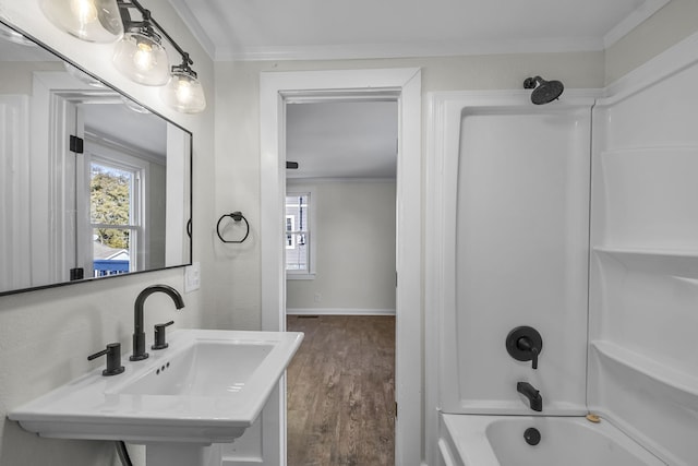 bathroom featuring bathtub / shower combination, hardwood / wood-style floors, crown molding, and sink