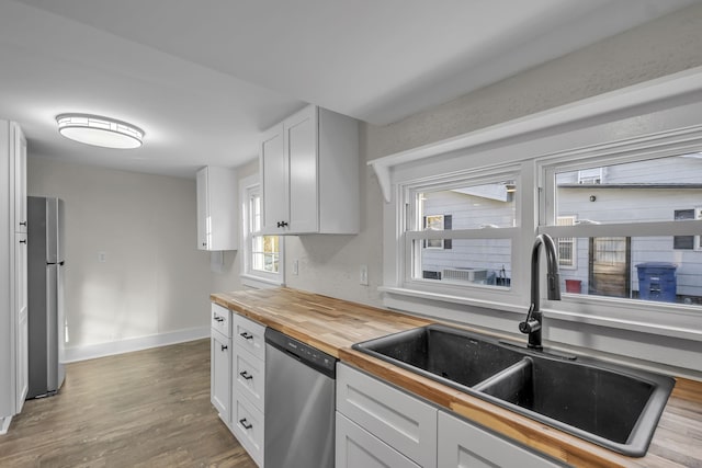 kitchen featuring white cabinets, appliances with stainless steel finishes, hardwood / wood-style floors, and wooden counters