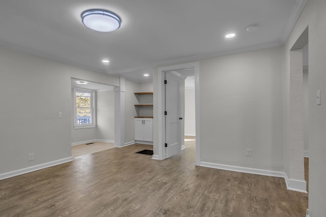 spare room with crown molding and wood-type flooring