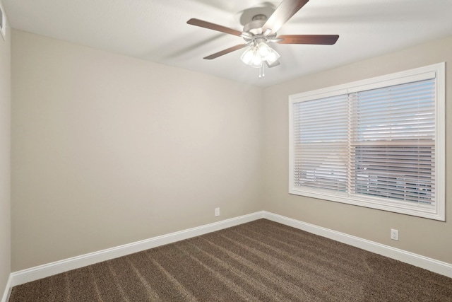 unfurnished room featuring ceiling fan, dark carpet, and baseboards