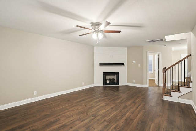 unfurnished living room with a large fireplace, baseboards, visible vents, dark wood-style floors, and stairs