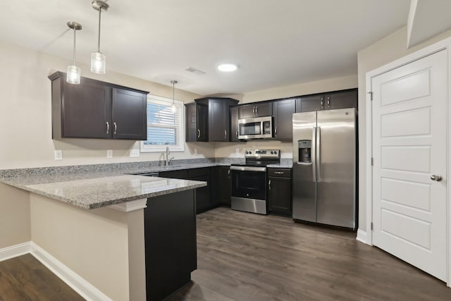 kitchen with dark wood finished floors, a peninsula, light stone countertops, stainless steel appliances, and a sink