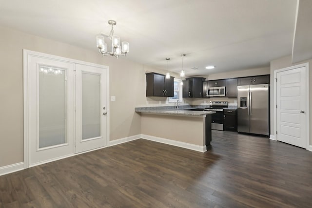 kitchen featuring baseboards, dark wood-type flooring, decorative light fixtures, a peninsula, and stainless steel appliances