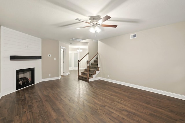 unfurnished living room featuring a large fireplace, visible vents, baseboards, stairs, and dark wood-style floors