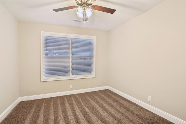 unfurnished room featuring baseboards, visible vents, dark carpet, and a ceiling fan