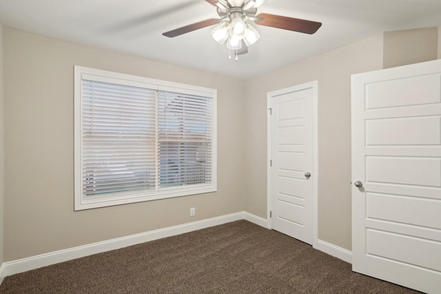 unfurnished bedroom featuring a ceiling fan, dark colored carpet, and baseboards