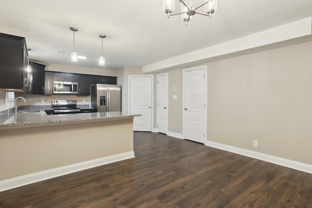 kitchen featuring stainless steel appliances, dark wood-type flooring, a sink, and light stone countertops